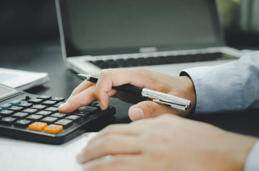 Hands using a calculator and laptop
