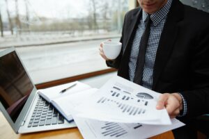 Businessman reviewing financial charts at a laptop by a window